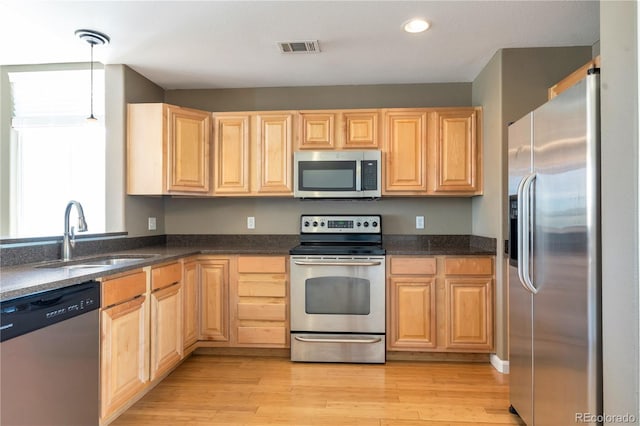 kitchen featuring visible vents, light brown cabinets, a sink, light wood-style flooring, and stainless steel appliances