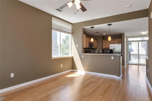 kitchen featuring a ceiling fan, visible vents, baseboards, a peninsula, and stainless steel appliances