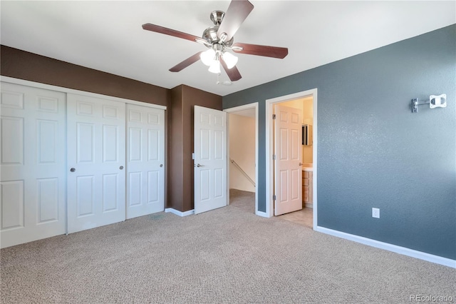 unfurnished bedroom featuring ceiling fan, light carpet, baseboards, ensuite bathroom, and a closet