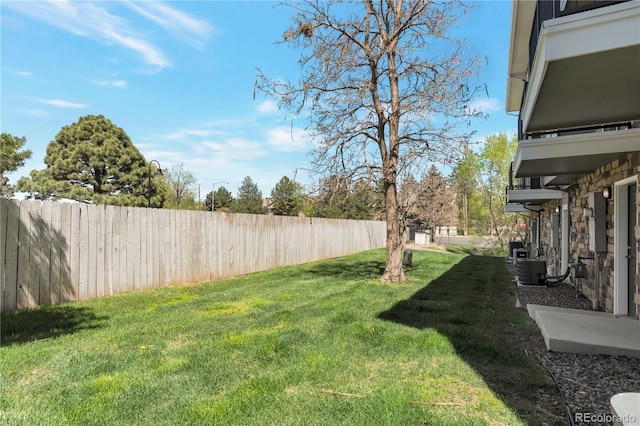 view of yard with central air condition unit and fence