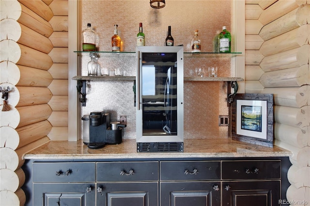 kitchen featuring wine cooler, light stone countertops, and rustic walls