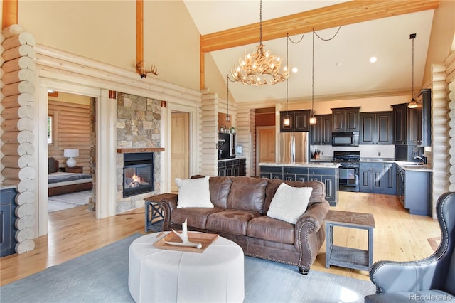 living room with light wood-type flooring, high vaulted ceiling, a chandelier, a stone fireplace, and log walls