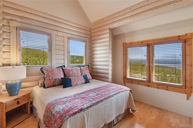 bedroom with multiple windows, lofted ceiling, hardwood / wood-style flooring, and log walls