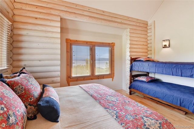 bedroom with rustic walls and light hardwood / wood-style flooring