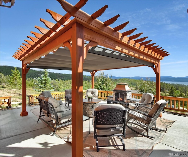 view of patio with a mountain view, exterior kitchen, a pergola, and an outdoor living space with a fireplace