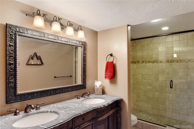 bathroom featuring a textured ceiling, vanity, toilet, and a shower with shower door