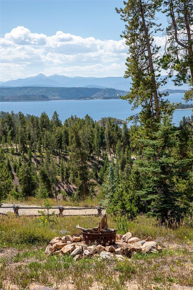 water view featuring an outdoor fire pit, a mountain view, and a view of trees