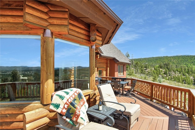 wooden deck with outdoor dining space and a wooded view