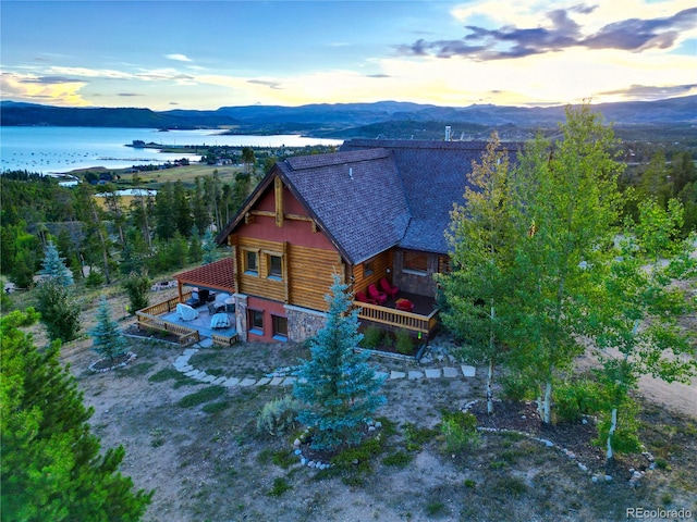 aerial view at dusk featuring a water and mountain view