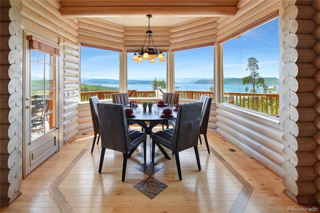 interior space with beamed ceiling, a water view, a notable chandelier, light hardwood / wood-style flooring, and log walls