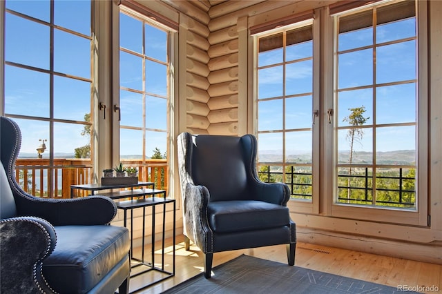 living area featuring hardwood / wood-style flooring, a wealth of natural light, and log walls