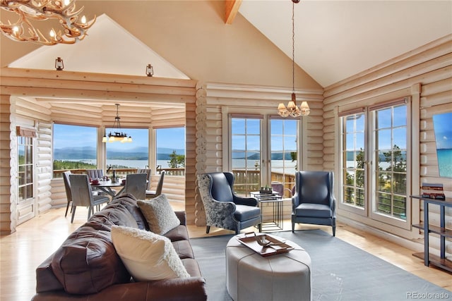 living room featuring high vaulted ceiling, a water view, a notable chandelier, and rustic walls