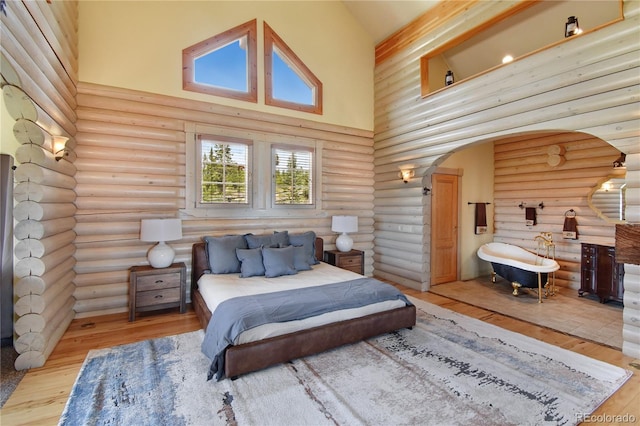 bedroom featuring rustic walls, high vaulted ceiling, and light hardwood / wood-style floors