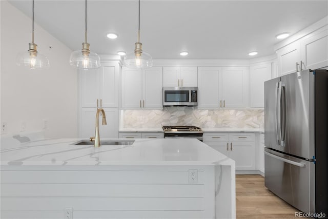 kitchen featuring white cabinetry, sink, hanging light fixtures, stainless steel appliances, and light stone countertops