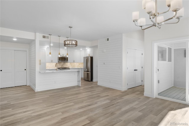 kitchen with white cabinetry, an inviting chandelier, decorative light fixtures, light hardwood / wood-style flooring, and appliances with stainless steel finishes