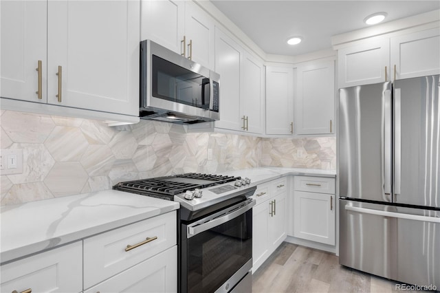 kitchen featuring backsplash, appliances with stainless steel finishes, white cabinets, and light stone counters