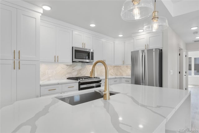 kitchen featuring hanging light fixtures, backsplash, appliances with stainless steel finishes, white cabinets, and light stone countertops