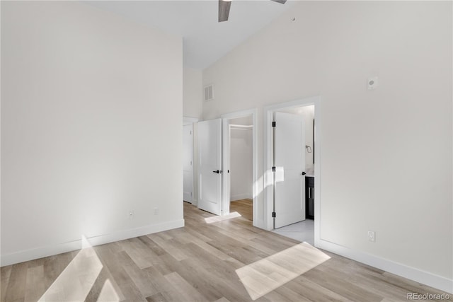 unfurnished bedroom featuring light wood finished floors, a high ceiling, visible vents, and baseboards