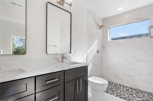 full bath featuring double vanity, a marble finish shower, visible vents, marble finish floor, and a sink