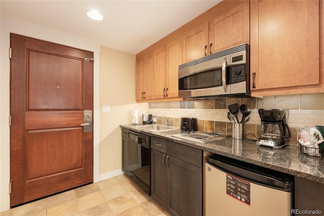 kitchen with stovetop, black dishwasher, dark stone counters, decorative backsplash, and sink