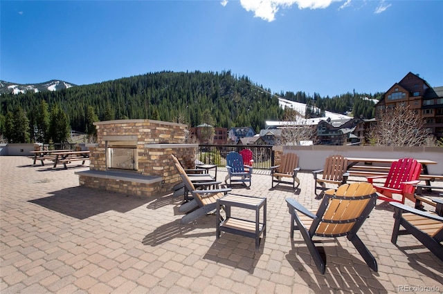 view of patio featuring a mountain view and an outdoor stone fireplace