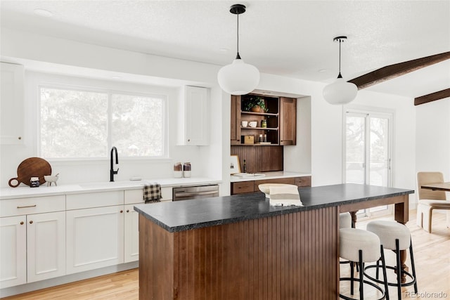 kitchen featuring a center island, decorative light fixtures, white cabinetry, and dishwasher