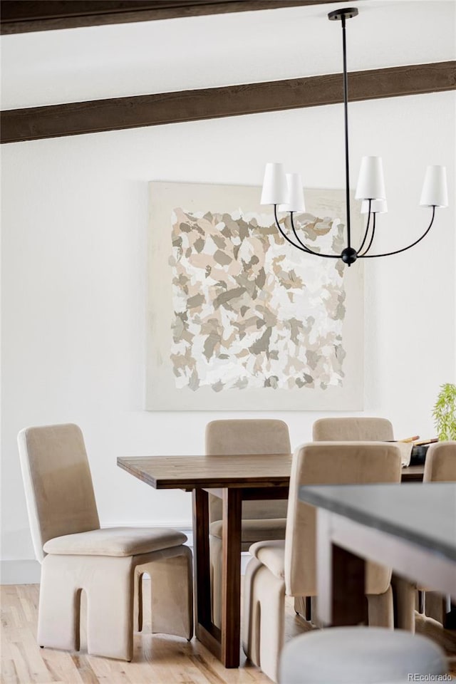 dining area with light wood-type flooring and an inviting chandelier