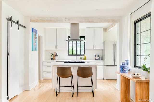 1300 N Glencoe St, Denver, CO 80220 - kitchen featuring high end refrigerator, island range hood, light wood-type flooring, a barn door, and white cabinetry
