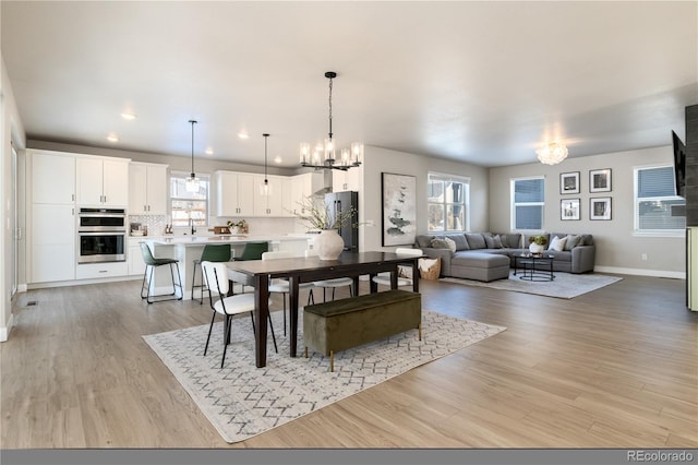 dining room with sink, plenty of natural light, light hardwood / wood-style floors, and a chandelier