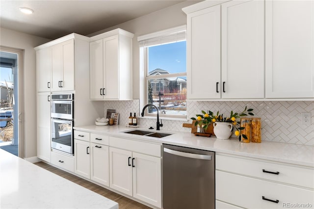 kitchen featuring sink, white cabinets, stainless steel appliances, light stone countertops, and backsplash