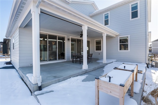 snow covered back of property with ceiling fan