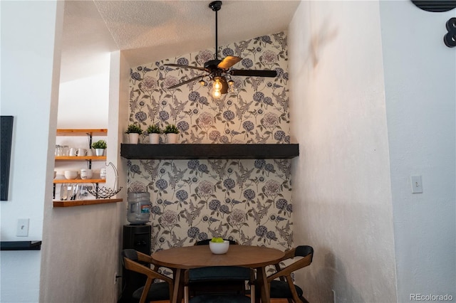 dining room featuring ceiling fan, a textured ceiling, and wallpapered walls