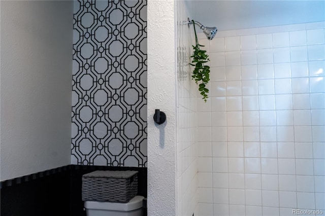 bathroom with tiled shower and a textured wall