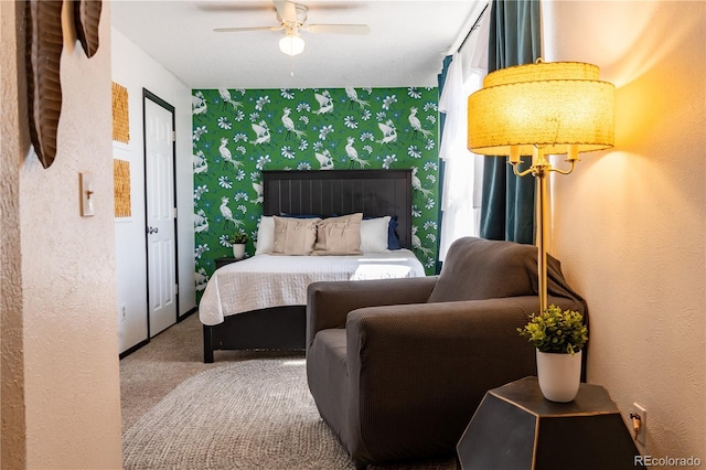 carpeted bedroom with ceiling fan with notable chandelier, an accent wall, and wallpapered walls