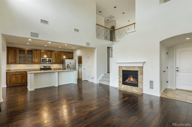 unfurnished living room featuring a high ceiling, dark hardwood / wood-style floors, and a fireplace