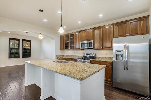 kitchen with light stone counters, stainless steel appliances, sink, and dark hardwood / wood-style flooring