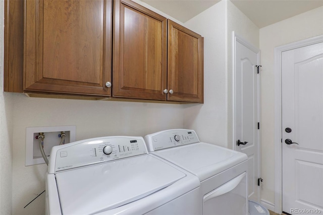 clothes washing area with cabinets and washing machine and dryer