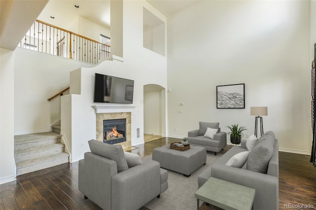 living room with a high ceiling, a tile fireplace, and dark hardwood / wood-style floors