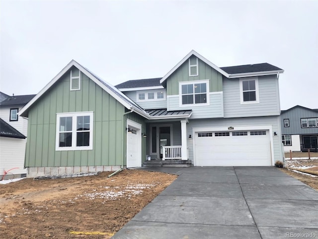 view of front of property featuring a garage, board and batten siding, driveway, and a standing seam roof