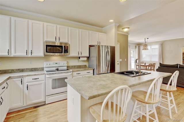 13025 Umatilla Ct, Denver, CO 80234 - kitchen featuring stainless steel appliances, ornamental molding, light wood-style flooring, white cabinetry, and recessed lighting