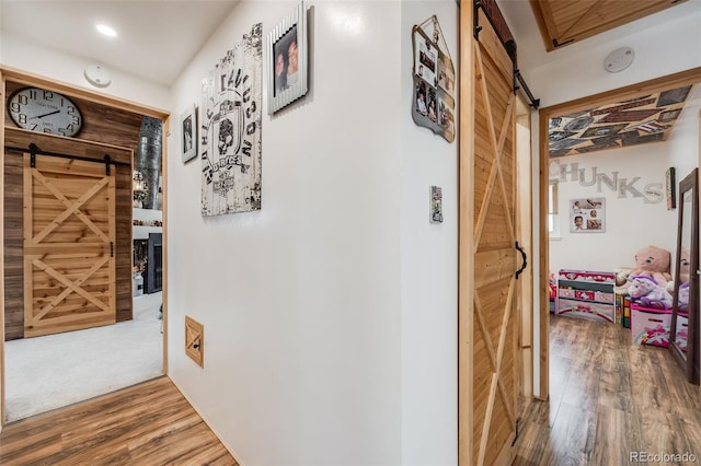 hallway with wood-type flooring and a barn door