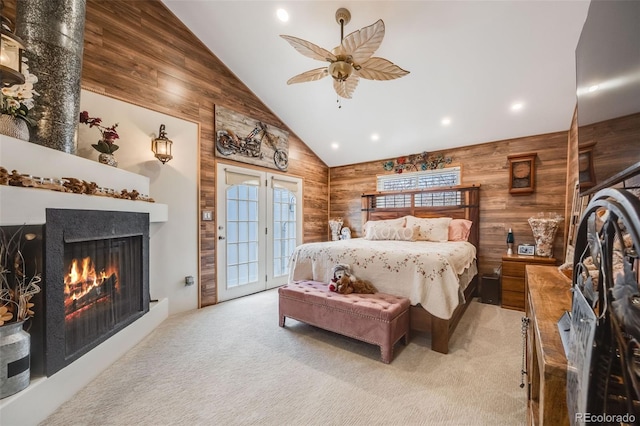 bedroom featuring high vaulted ceiling, wood walls, access to exterior, ceiling fan, and light carpet