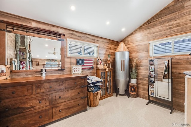 miscellaneous room with vaulted ceiling, light colored carpet, and wooden walls