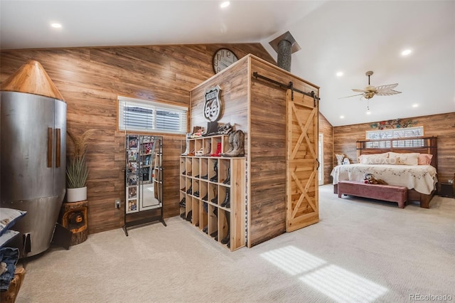 bedroom with vaulted ceiling, a barn door, and wood walls