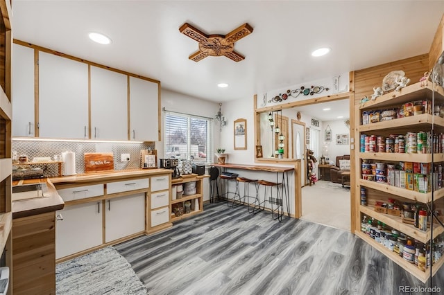 kitchen with white cabinetry, tasteful backsplash, kitchen peninsula, and light wood-type flooring