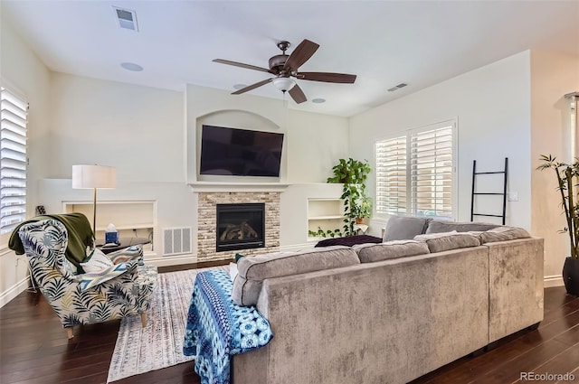 living area featuring visible vents, dark wood finished floors, and a glass covered fireplace