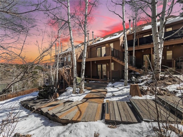 snow covered property featuring a deck and stairway