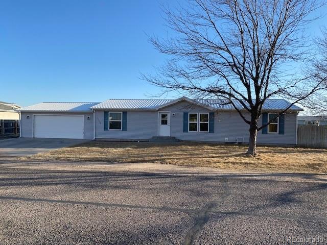 single story home with concrete driveway, metal roof, an attached garage, and fence