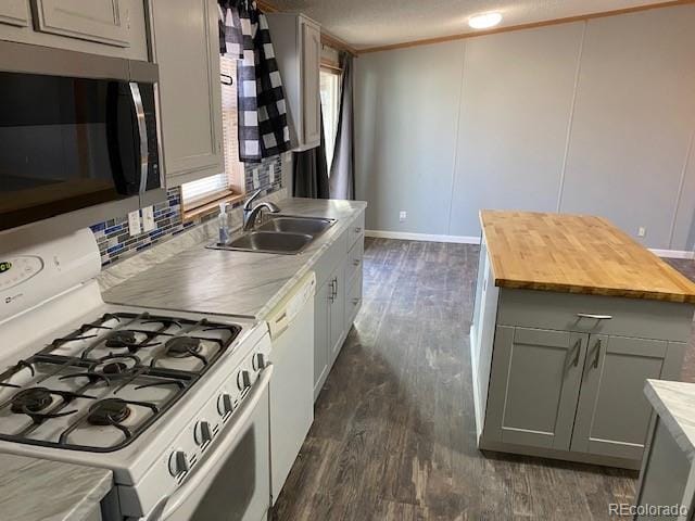 kitchen featuring white appliances, butcher block countertops, dark wood-type flooring, gray cabinetry, and a sink