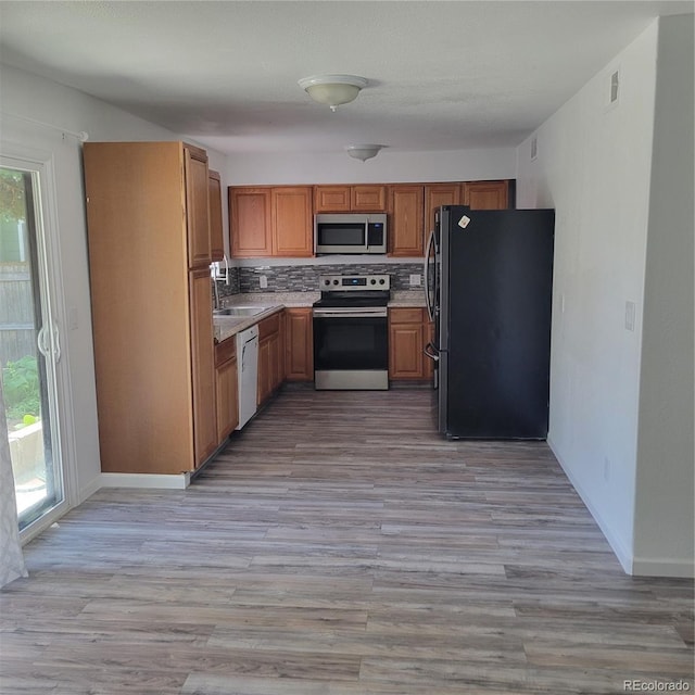 970 S Peoria St, Aurora, CO 80012 - kitchen with stainless steel appliances, light wood finished floors, light countertops, decorative backsplash, and brown cabinets
